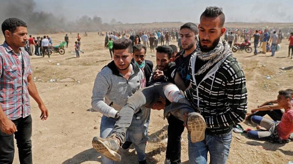 Palestinians carry a demonstrator injured during clashes with Israeli forces near the border between the Gaza strip. (AFP)