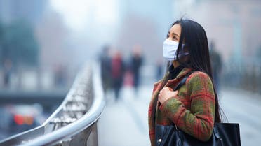 Young woman wearing mask in the foggy city - Stock image