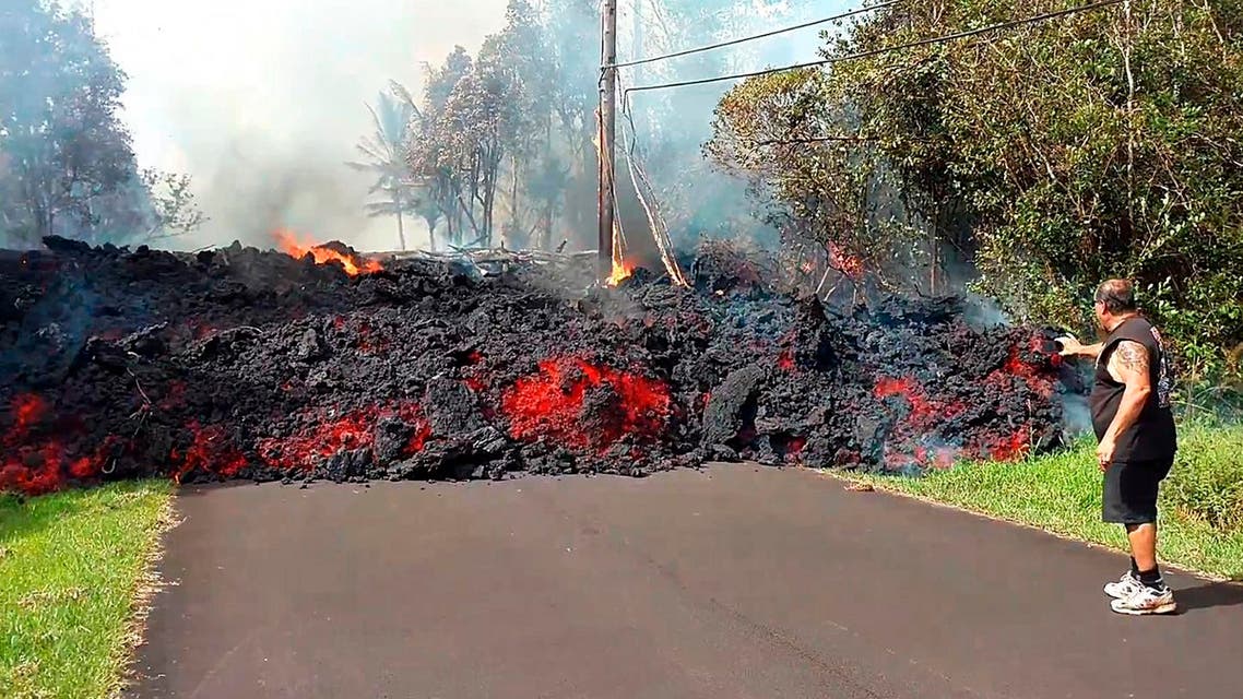 man gets close to a lava flow advancing down a road in the Leilani Estates subdivision near Pahoa on the island of Hawaii Monday, May 7, 2018. (AP)