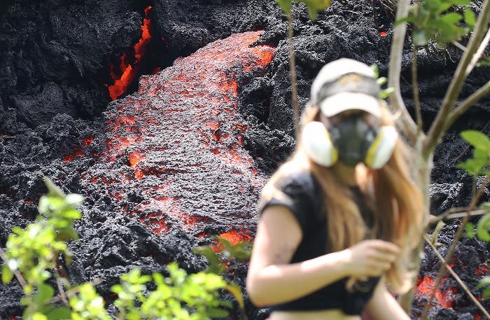 Lava flows at a new fissure in the aftermath of eruptions from the Kilauea volcano on Hawaii's Big Island as a local resident walks nearby after taking photos on May 12, 2018 in Pahoa. (AP)
