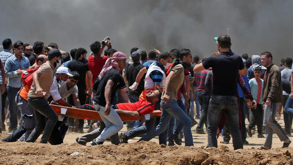 Palestinian men carry an injured protester during clashes with Israeli forces near the border between Israel and the Gaza strip, east of Jabalia on May 14, 2018. (AFP)