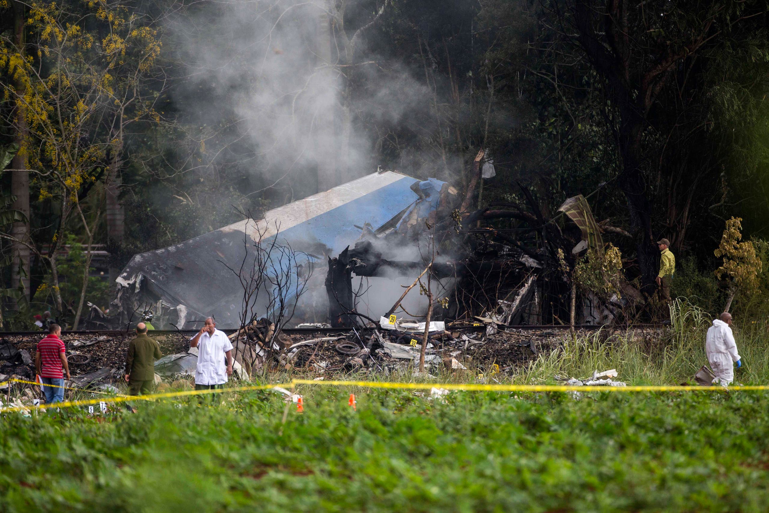EDS NOTE: GRAPHIC CONTENT - Investigators work near the smoldering remains of a Boeing 737 that plummeted into a yuca field just after takeoff with more than 100 passengers on board, in Havana, Cuba, Friday, May 18, 2018. (AP Photo/Desmond Boylan)