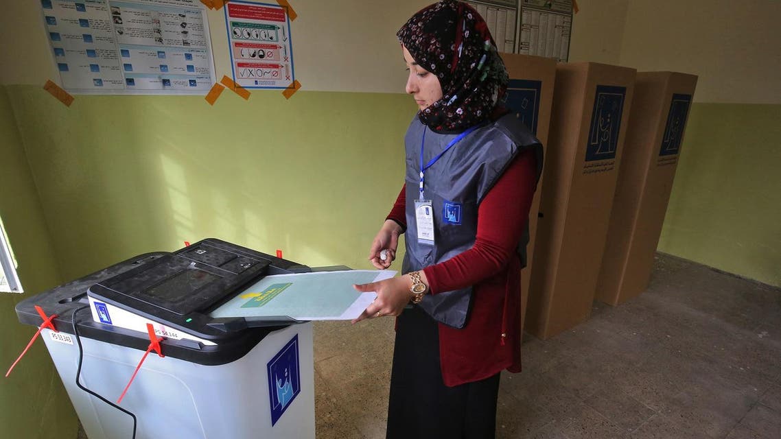 An Iraqi election registrar places a ballot through an electronic counting machine at a polling station in Mosul on May 12, 2018. (AFP)