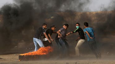 Palestinian demonstrators drag a burning tire during a protest demanding the right to return to their homeland, at the Israel-Gaza border in the southern Gaza Strip May 25, 2018. REUTERS/Ibraheem Abu Mustafa TPX IMAGES OF THE DAY