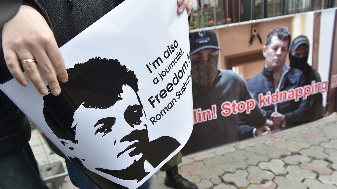 Ukrainian journalists hold placards depicting their colleague Roman Sushchenko during a protest to call for the release of a Ukrainian journalist detained in Moscow for spying. (AFP)