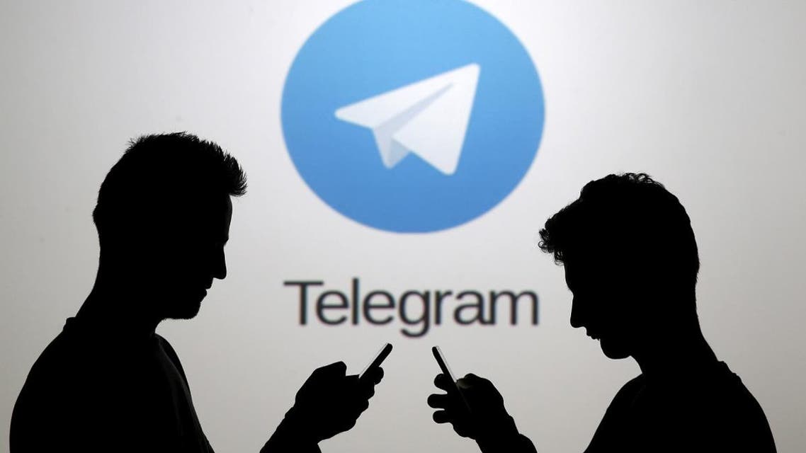 Two men pose with smartphones in front of a screen showing the Telegram logo in this picture illustration.