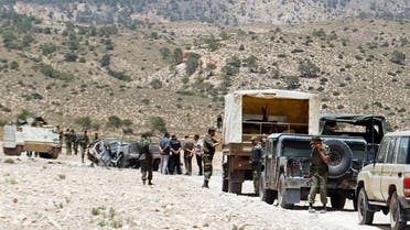 Tunisian army stand guard near a demolished vehicle following a roadside bomb in the mountainous border region near Algeria where security forces have been hunting Al-Qaeda linked jihadists, on June 6, 2013. Two soldiers were killed and two others wounded when a device exploded as their vehicle passed by in the Doghra area of Mount Chaambi. AFP PHOTO / ABDERRAZEK KHLIFI