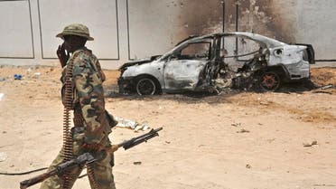 A Somali soldier patrols next to the burnt-out wreckage of a car that was used by suspected al-shabab fighters on April 16, 2017. (AFP)