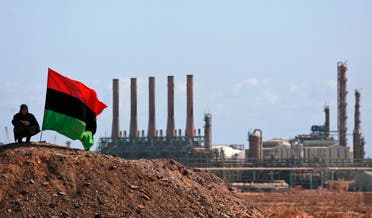 A Libyan rebel who is part of the forces against Libyan leader Moammar Gadhafi sits next to a pre-Gadhafi flag as he guards outside the refinery in Ras Lanuf, eastern Libya. (File Photo: Reuters)