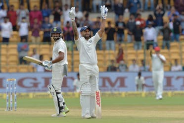 Indian cricketer Murali Vijay (L) looks on as teammate Shikhar Dhawan (C) celebrates his century (100 runs) during the first day of the one-off cricket Test match between India and Afghanistan in Bangalore on June 14, 2018. (AFP)