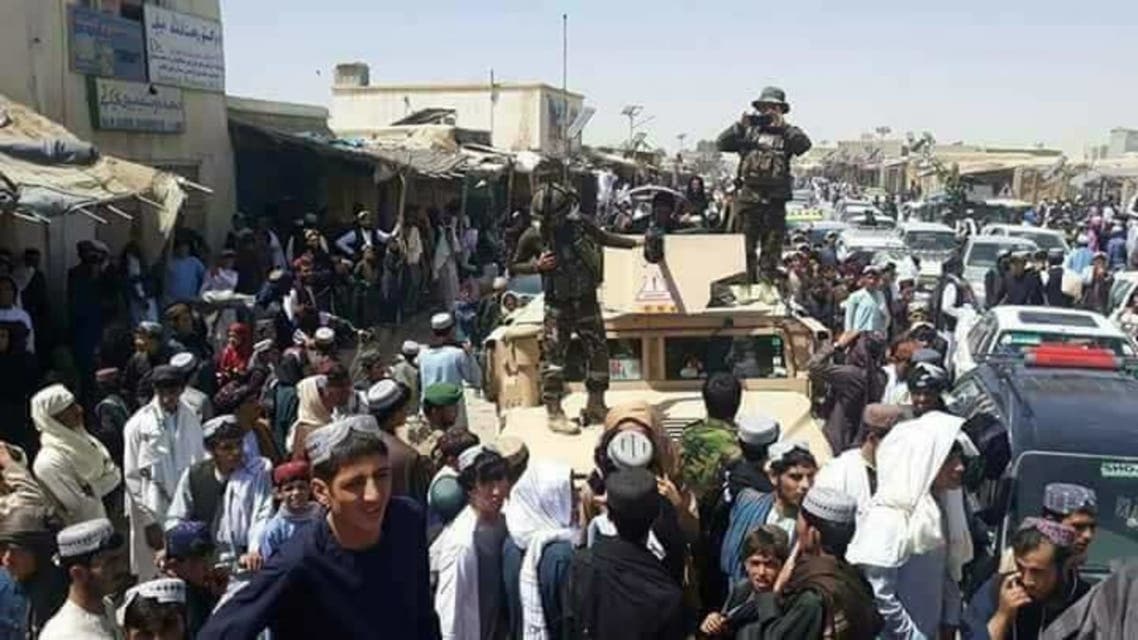 عناصر طالبان يجتمعون حول سيارة عسكرية حكومية