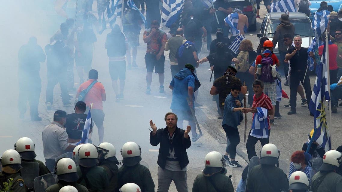 Protestors holding Greek flags walk amid smoke during a protest at the village of Pisoderi near the border with Macedonia in northern Greece on July 17, 2018. (AFP)