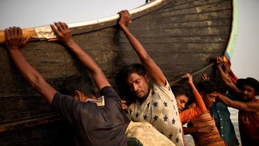 Rohingya refugees push a fishing boat from the sea at Shamlapur beach in Cox's Bazar, Bangladesh. (Reuters)