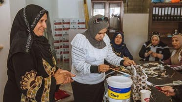 Syrian refugee Sameera Al Salam shows a colleague how to strengthen a paper handbag with glue, at an up-cycling workshop in Irbid city, northern Jordan, May 9, 2018. (Photo: Freya Dowson/Action Against Hunger)