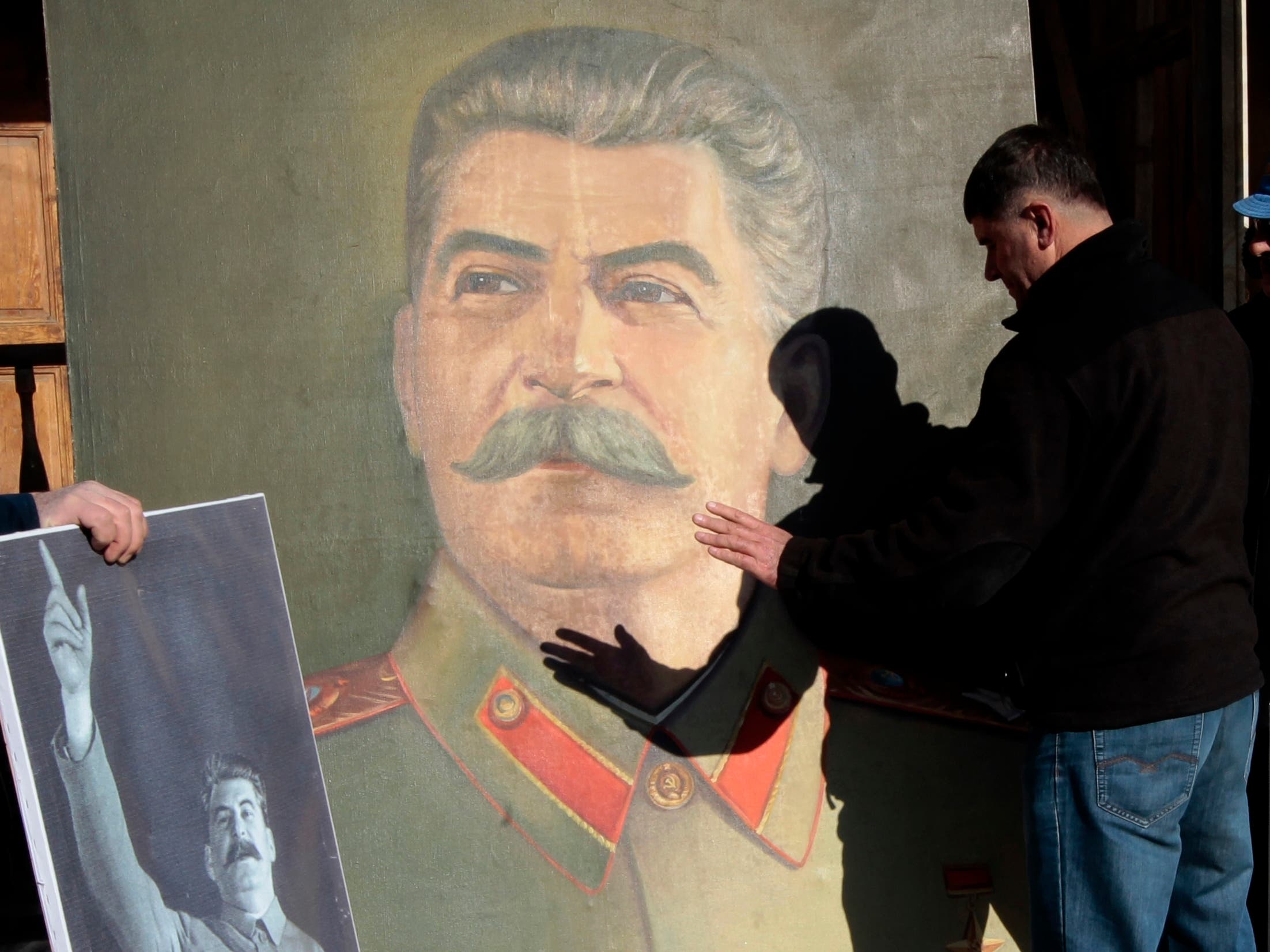 A Georgian man plays with a shadow on a portrait of Soviet dictator Joseph Stalin, during a rally marking Stalin's birthday in his home town of Gori, some 80 km (50 miles) west of the Georgian capital Tbilisi. (AP)
