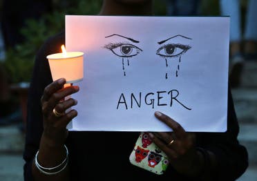 In this April 16, 2018, file photo, a woman holds a candle and placard seeking an end to sexual violence against women. (AP)