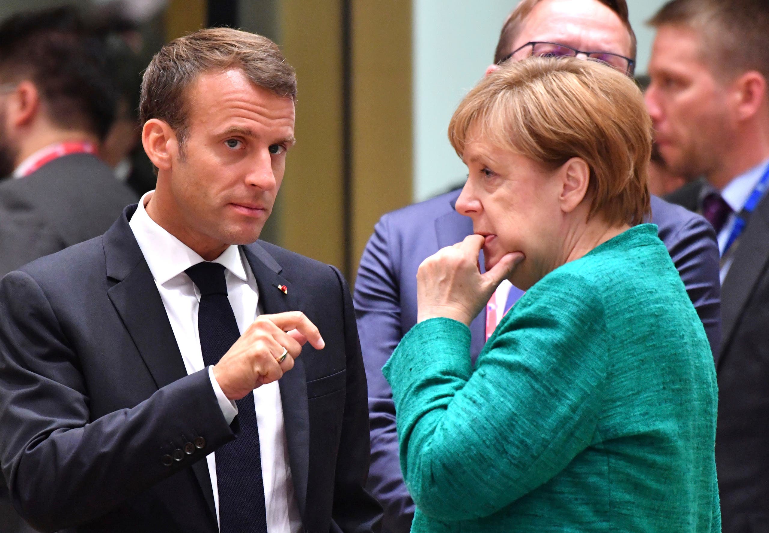 French President Emmanuel Macron, left, speaks with German Chancellor Angela Merkel during a round table meeting at an EU summit in Brussels, Thursday, June 28, 2018.