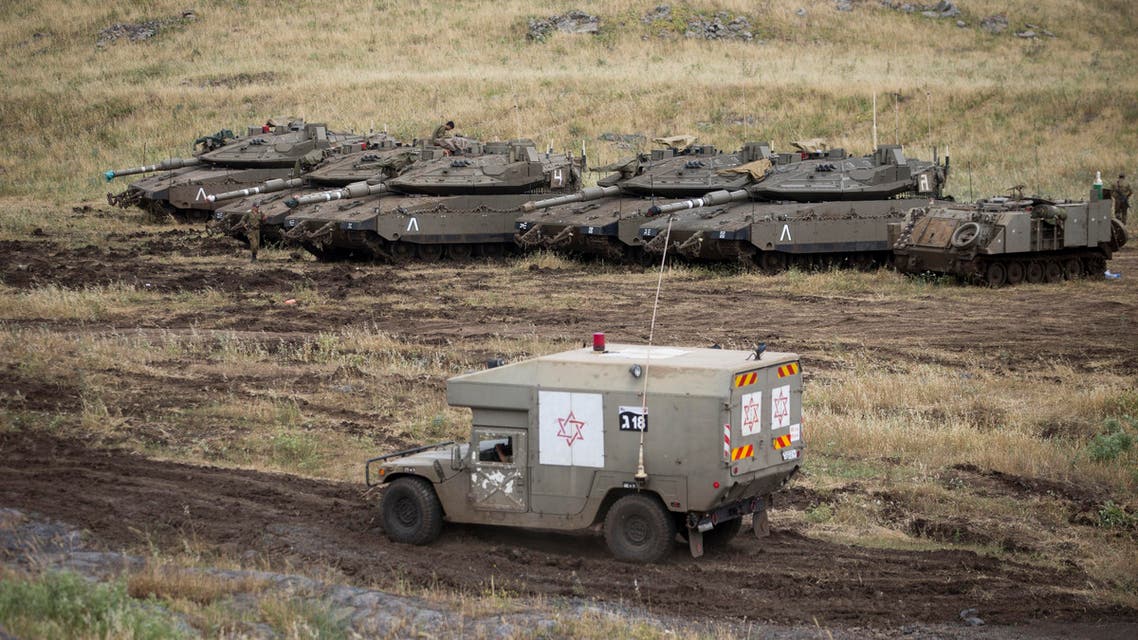 An Israeli military ambulance drives past tanks in the Israeli-controlled Golan Heights, near the border with Syria. (AP)