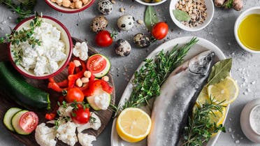 Mediterranean style food background. Fish, vegetables, herbs, chickpeas, olives, cheese on grey background, top view. Healthy food concept. Flat lay - Stock image