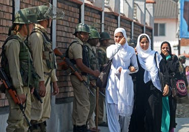 Indian paramilitary troopers stand guard as Kashmiri Muslim school girls walk past in Srinagar on October 1, 2013. (AFP)