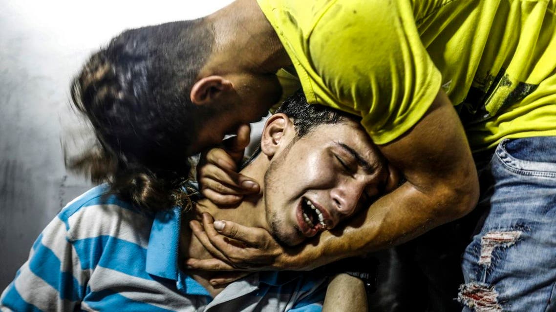 Palestinian youths mourn at al-Shifa hospital morgue on July 14, 2018 after two teenagers were killed in one of a series of Israeli raids. (AFP)