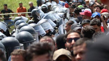 Iraqi security forces form a human barrier as protesters demonstrate against unemployment and a lack of basic services in the southern Iraqi city of Basra on July 15, 2018. Dozens of demonstrators were wounded today as the ongoing protests hit several Iraqi provinces including Basra, despite Prime Minister Haider al-Abadi announcing fresh funds and pledges of investment for the oil-rich but neglected region.