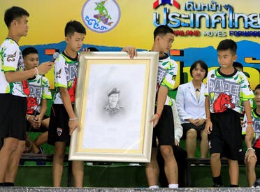 A 'Wild Boars' player holds a portrait of former Navy SEAL diver Saman Kunan, who died during the rescue operation, as they pay respect during their news conference in Chiang Rai, Thailand. (Reuters)