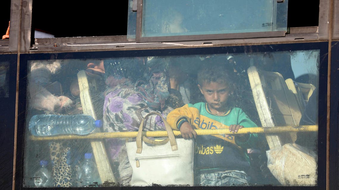 A Syrian child lokks through the windows of a bus as displaced people from the Quneitra province wait at the Murak crossing point to be carried in the provinces of Idlib and Aleppo, in Murak, northwestern Syria, on July 21, 2018. The transfers come under a surrender deal agreed this week between Russia and Syrian rebels in Quneitra province that will see the sensitive zone fall back under state control. Rebels will hand over territory they control in Quneitra and the neighbouring buffer zone with the Israeli-occupied Golan, a war monitor and a rebel source told AFP.