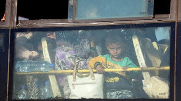 A Syrian child lokks through the windows of a bus as displaced people from the Quneitra province wait at the Murak crossing point to be carried in the provinces of Idlib and Aleppo, in Murak, northwestern Syria, on July 21, 2018. The transfers come under a surrender deal agreed this week between Russia and Syrian rebels in Quneitra province that will see the sensitive zone fall back under state control. Rebels will hand over territory they control in Quneitra and the neighbouring buffer zone with the Israeli-occupied Golan, a war monitor and a rebel source told AFP.