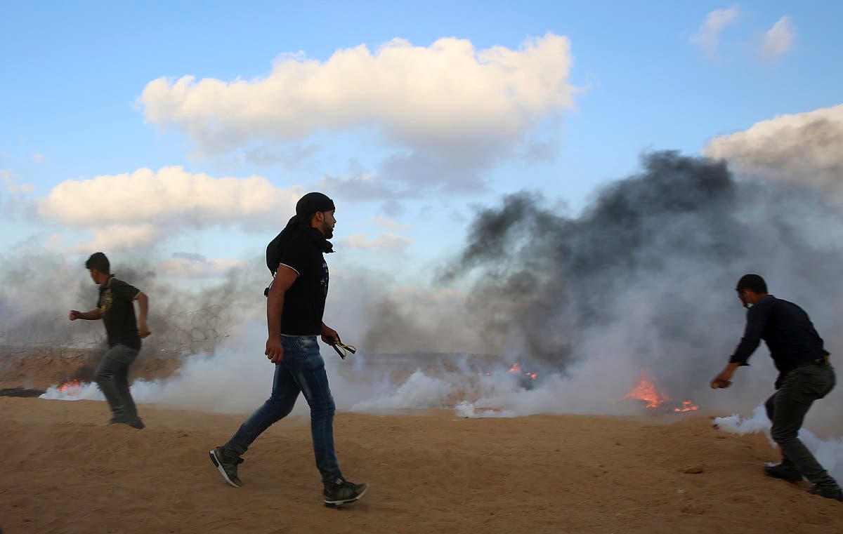 Protesters try to throw back teargas canisters fired by Israeli troops near the fence of the Gaza Strip border with Israel, during a protest east of Khan Younis, southern Gaza Strip, Friday, July 20, 2018. (AP)