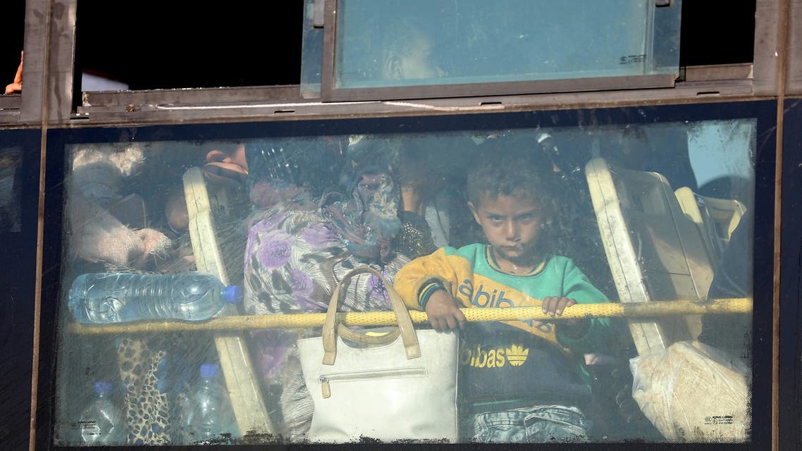 A Syrian child lokks through the windows of a bus as displaced people from the Quneitra province wait at the Murak crossing point to be carried in the provinces of Idlib and Aleppo, in Murak, northwestern Syria, on July 21, 2018. The transfers come under a surrender deal agreed this week between Russia and Syrian rebels in Quneitra province that will see the sensitive zone fall back under state control. Rebels will hand over territory they control in Quneitra and the neighbouring buffer zone with the Israeli-occupied Golan, a war monitor and a rebel source told AFP.