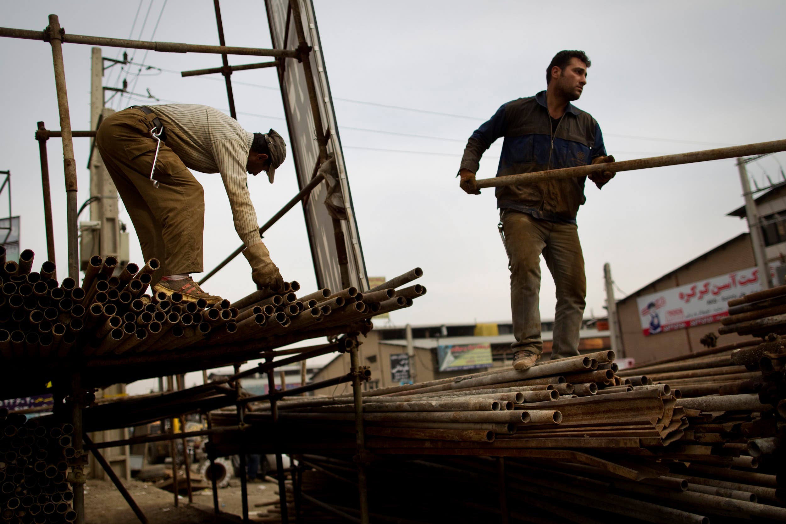 Iranian workers load scaffolding onto a pick-up truck at an iron market in Tehran on February 25, 2012. (File photo: AFP)
