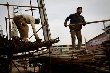 Iranian workers load scaffolding onto a pick-up truck at an iron market in Tehran on February 25, 2012. (File photo: AFP)
