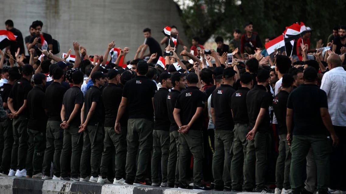 Security forces stand guard as Iraqis wave national flags and hold up signs during a demonstration against unemployment in the capital Baghdad's Tahrir Square on July 27, 2018. (AFP)