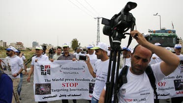 Palestinian journalists hold a banner with photos of two journalists recently killed in Gaza during a protest near Ramallah, on May 6, 2018. (File photo: AFP)
