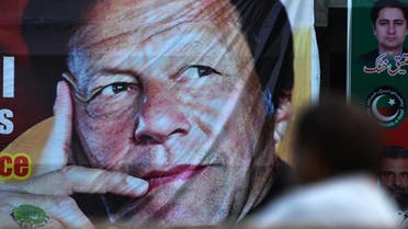 A Pakistani man sits near a poster of Imran Khan in Islamabad on July 30, 2018. (AFP)