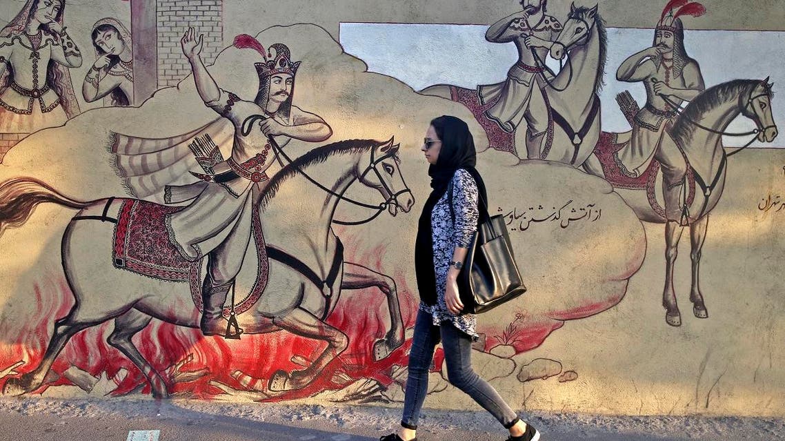 An Iranian woman walks past paintings of a Persian poetry in downtown Tehran, Iran, Monday, July 30, 2018. (AP)