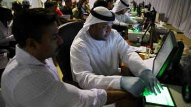 A government employee, left, takes the fingerprints of a foreign worker at a visa processing center in Al Aweer, about 30 km east of Dubai, on Aug. 1, 2018. (AP)
