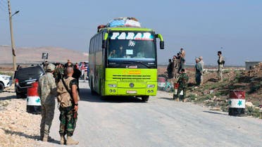 This photo released by the Syrian official news agency SANA, shows Syrian troops overseeing the evacuation of people in buses