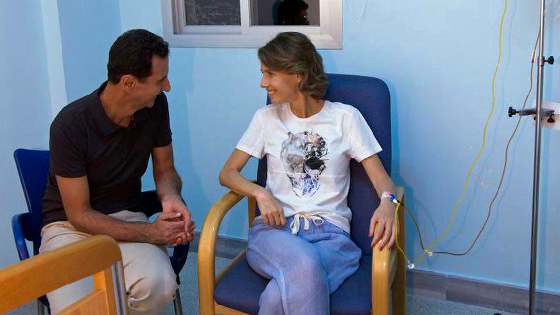 President Bashar Assad sitting next to his wife in a hospital room with an IV in her left arm. (AP)