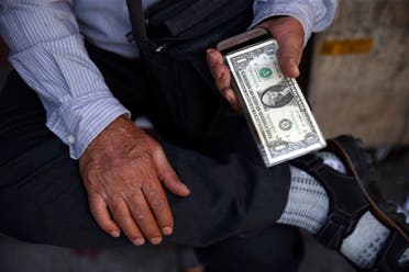 An Iranian street money exchanger holds US banknote in Tehran on July 30, 2018. (AP)