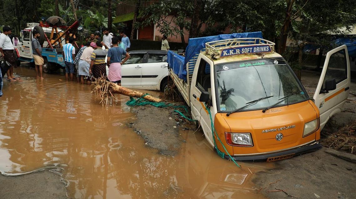 People look at vehicles stuck in the mud along a flooded road at Kannappankundu in Kozhikode, in the South Indian state of Kerala on August 10, 2018. (AFP)
