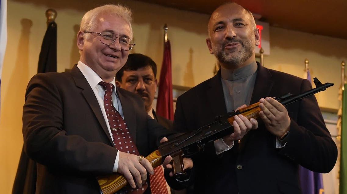 Russian Ambassador to Afghanistan Alexander Mantytskiy (L) hands over a AK-47 rifle to Afghan National Security Adviser Hanif Atmar (R) during a ceremony at a military airfield in Kabul. (AFP)