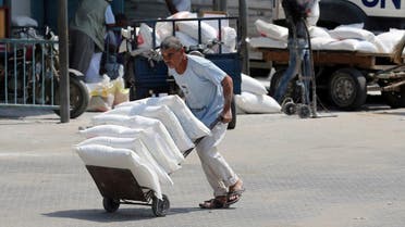 Palestinian man pushes a cart with bags of flour at an aid distribution center run by UNRWA in Khan Younis. (Reuters)