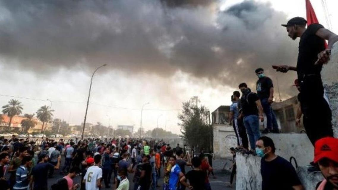 Protestors react in front of burning building in Basra, southeast of Baghdad, Iraq, on Thu