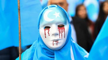 A person wearing a white mask with tears of blood takes part in a protest march in Brussels in support of ethnic Uighurs. (AFP)