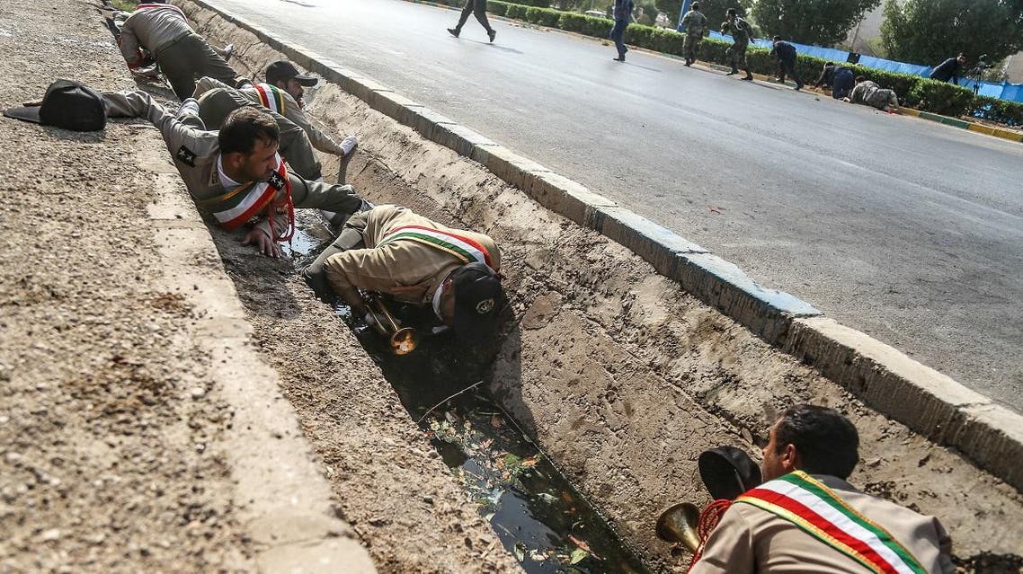This picture taken on September 22, 2018 in the southwestern Iranian city of Ahvaz shows Iranian soldiers taking cover in a rain gutter off a street at the scene of an attack on a military parade. (AFP)