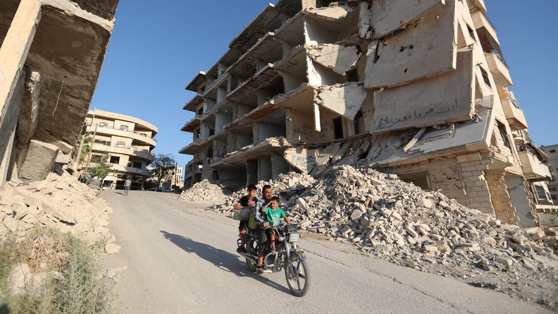 Syrian men ride a motorcycle past heavily-damaged buildings in the rebel-held town of Maaret al-Numan, in the north of Idlib province on September 27, 2018.