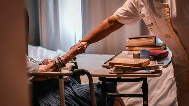 An elderly resident holds the forearm of a nurse on July 5, 2018, in an establishment of accommodation for dependent elderly (EHPAD) in Paris. 