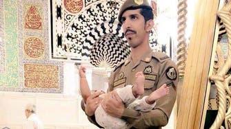 Heartwarming photo shows Saudi officer carries child as father performs prayer 